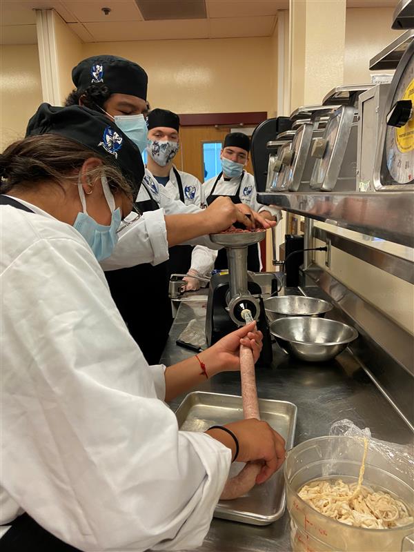Culinary Students learning how to add meat to brat casing